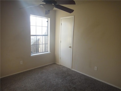 Carpeted empty room featuring a ceiling fan and ba