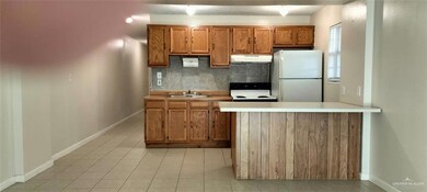 Kitchen with tasteful backsplash, white appliances, under cabinet range hood, a sink, and brown cabinetry