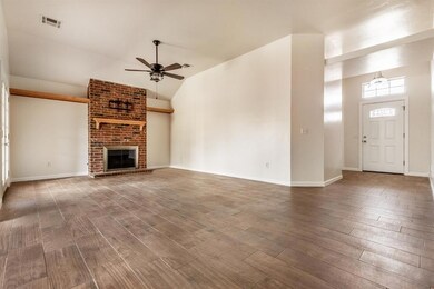 Unfurnished living room with ceiling fan, wood finished floors, vaulted ceiling, a brick fireplace, and baseboards