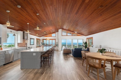 Kitchen with gray cabinetry, decorative light fixtures, a center island, light wood-style flooring, and healthy amount of natural light