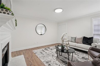 Living room with light wood-style flooring, crown molding, and a fireplace with flush hearth