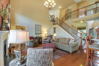 Family Room is a dramatic 2 story space with accent wall, gas fireplace, hardwood floors, custom window treatments, chandelier, and open to the kitchen.