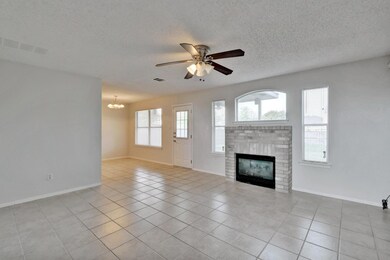 Unfurnished living room featuring light tile patterned flooring, a brick fireplace, ceiling fan, a chandelier, and a textured ceiling