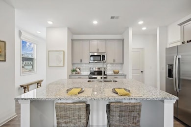 Kitchen featuring stainless steel appliances, light stone counters, dark hardwood / wood-style floors, and backsplash
