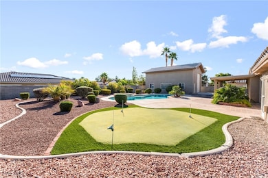 Fenced backyard with an area to practice putting and a patio