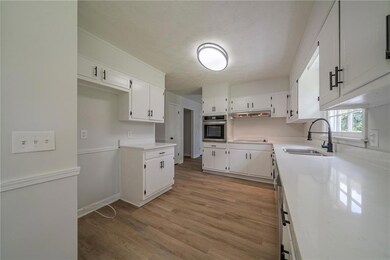 Kitchen featuring oven, light wood-style flooring, white cabinets, a sink, and a textured ceiling