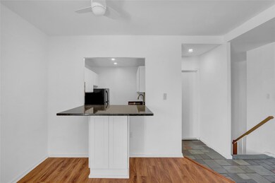 Kitchen with freestanding refrigerator, white cabinets, a ceiling fan, wood finished floors, and dark countertops