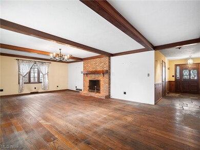 Unfurnished living room featuring dark hardwood / wood-style flooring, a healthy amount of sunlight, a brick fireplace, and a chandelier