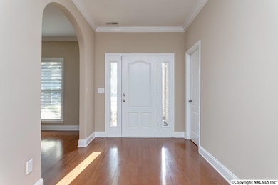 Entry foyer with gleaming hardwoods and crown molding.