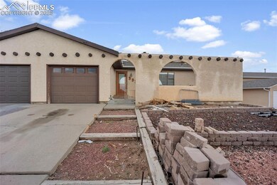 Pueblo-style house featuring concrete driveway, st