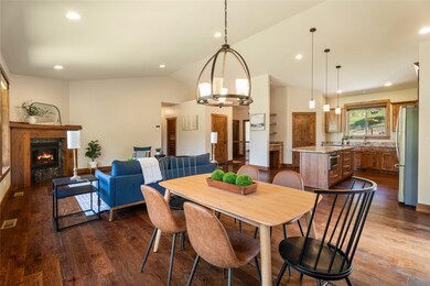 Dining area with vaulted ceiling, a high end fireplace, dark wood finished floors, and recessed lighting
