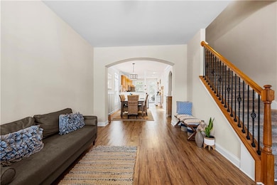 Living room featuring arched walkways, wood finished floors, and stairs
