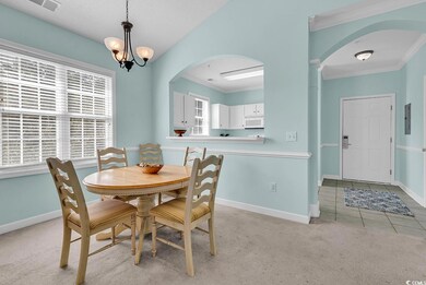 Carpeted dining area with arched walkways, ornamental molding, a chandelier, and tile patterned floors
