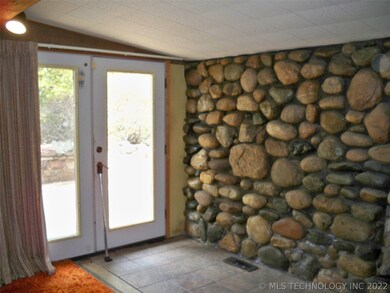 Front door at mid level with rock wall & fireplace