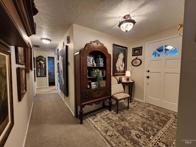 Carpeted entryway with a textured ceiling and baseboards