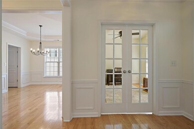 Entryway with a decorative wall, light wood-style flooring, french doors, a raised ceiling, and a chandelier