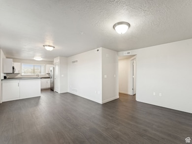 Unfurnished living room with dark wood-style floors and a textured ceiling