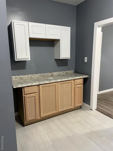 Kitchen with light wood-type flooring and light stone counters