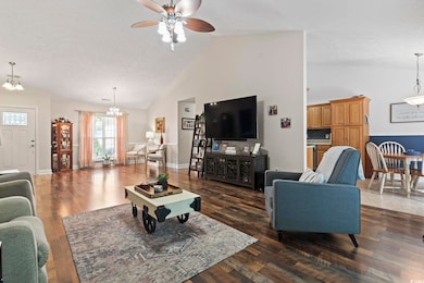 Living room featuring a chandelier, a ceiling fan, high vaulted ceiling, and wood finished floors