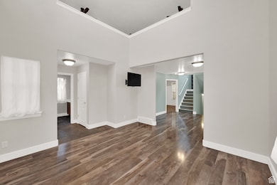 Spare room with dark wood-style floors, stairway, a high ceiling, and ornamental molding