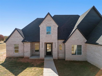 French country inspired facade with brick siding, a front yard, and a shingled roof
