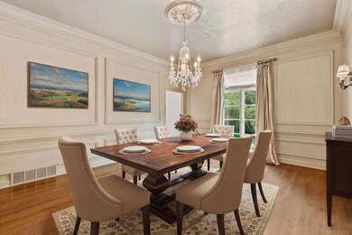 Elegant 17x14 Dining Room Featuring 10-Foot Smooth Ceiling, Crown Molding, Chair Rail, Shadowbox Wall Molding, and Fluted Door Trim — Perfect for Formal Gatherings! This photo is virtually staged.