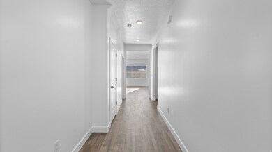 Corridor with a textured ceiling and light wood finished floors