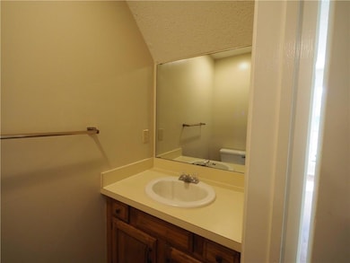 Bathroom with vanity, lofted ceiling, toilet, and