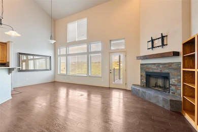 Unfurnished living room featuring high vaulted ceiling, dark wood-style flooring, and a fireplace