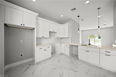 Kitchen featuring recessed lighting, light marble finish floors, white cabinetry, pendant lighting, and backsplash