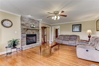 The Great Room.  Hardwood flooring continues into the Great Room. Base, crown and door case molding enhance the space. Gas log fireplace with stone hearth, mantel and surround. Ceiling fan with light, and accent lighting above the fireplace.