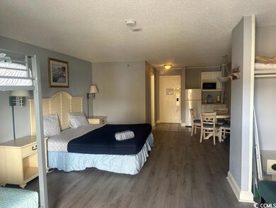 Bedroom with dark wood-type flooring, white fridge