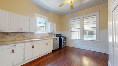 Kitchen with dark wood-style flooring, white cabinets, range with two ovens, crown molding, and dishwashing machine