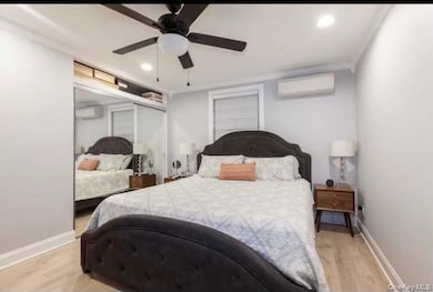 Bedroom featuring light wood-type flooring, recessed lighting, a wall mounted air conditioner, a ceiling fan, and an AC wall unit