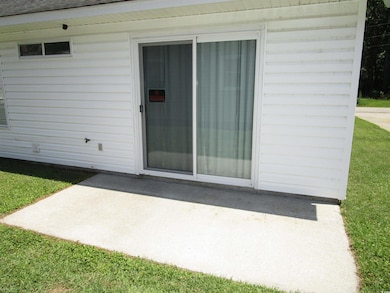 Doorway to property with a patio area, roof with shingles, and a yard