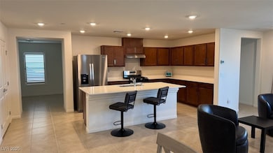 Kitchen with a kitchen bar, a center island with sink, stainless steel appliances, recessed lighting, and dark brown cabinets