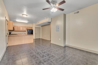 Unfurnished living room featuring dark tile patterned flooring, a ceiling fan, and electric panel