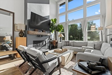 Living room featuring a glass covered fireplace, a towering ceiling, and wood finished floors