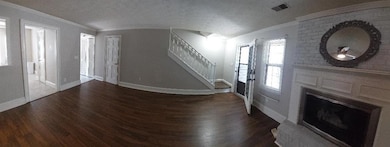 Foyer featuring stairs, wood finished floors, a fireplace, crown molding, and a textured ceiling