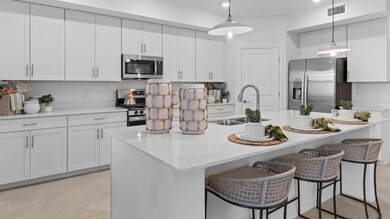 The center island offers space for added seating, overlooking the kitchen’s ample cabinetry and stainless steel appliances