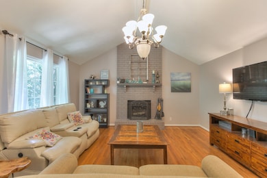 As you step into the living room you are greeted by vaulted ceilings, gleaming hardwood floors &  and a wood burning fireplace.