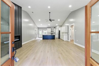Unfurnished living room featuring a ceiling fan, light wood finished floors, a fireplace, and high vaulted ceiling
