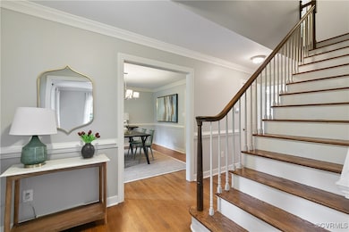Staircase with crown molding, wood finished floors