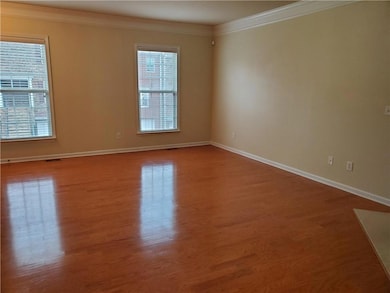 Unfurnished living room featuring crown molding, wood finished floors, baseboards, and a tiled fireplace