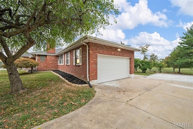 View of property exterior with brick siding, driveway, a lawn, and a garage