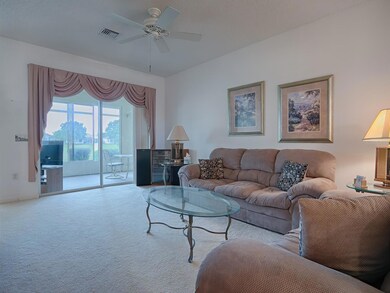 SPACIOUS LIVING ROOM WITH A VIEW THROUGH THE LANAI TO THE GOLF COURSE BEYOND