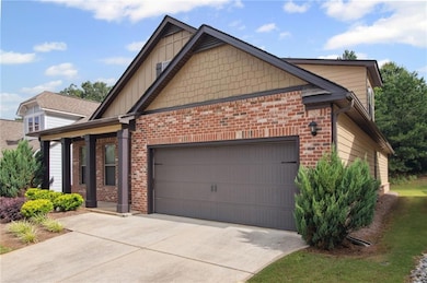 View of side of home featuring driveway, an attached garage, and brick siding
