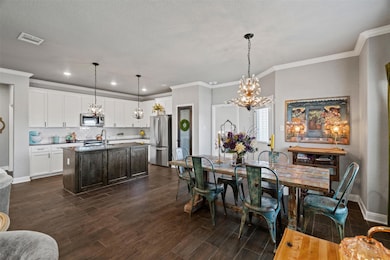 Dining room featuring a chandelier, crown molding, dark wood finished floors, and recessed lighting