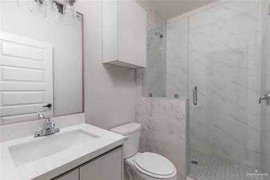 Bathroom with a shower stall, toilet, and vanity