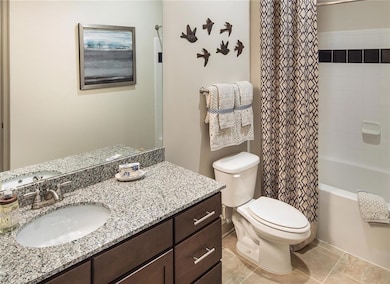 Full bathroom with tile floors, large vanity, toil